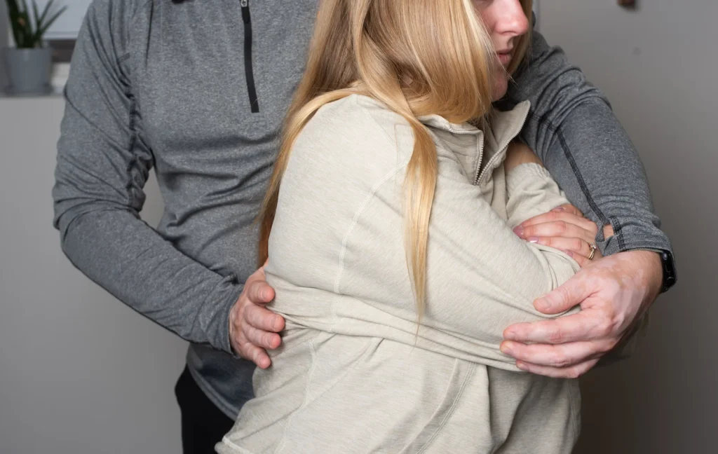 What Is Manual Osteopathy? A Practitioner Reveals What It Actually Does 1 Photo of Dmitro Jovnyruk at JD Osteopathy, treating a patient's mid back and ribs to affect the spine and lower back of the patient. Photo shows Dmitro using the patients elbow to create a rotation of the patient in seating position to illustrate what is manual osteopathy in principle.