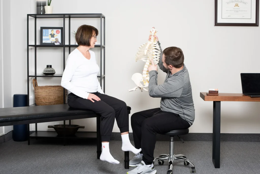 Patient being shown osteopathy through a demo skeleton by the osteopathic practitioner, Dmitro, at JD Osteopathy Mississauga