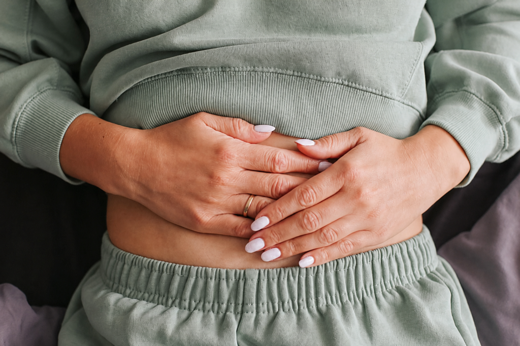 Osteopathy for Digestion: Why It Is Rarely Just a Gut Problem 1 Woman holding her abdominal area seeking to get help with Osteopathy for Digestion complaints